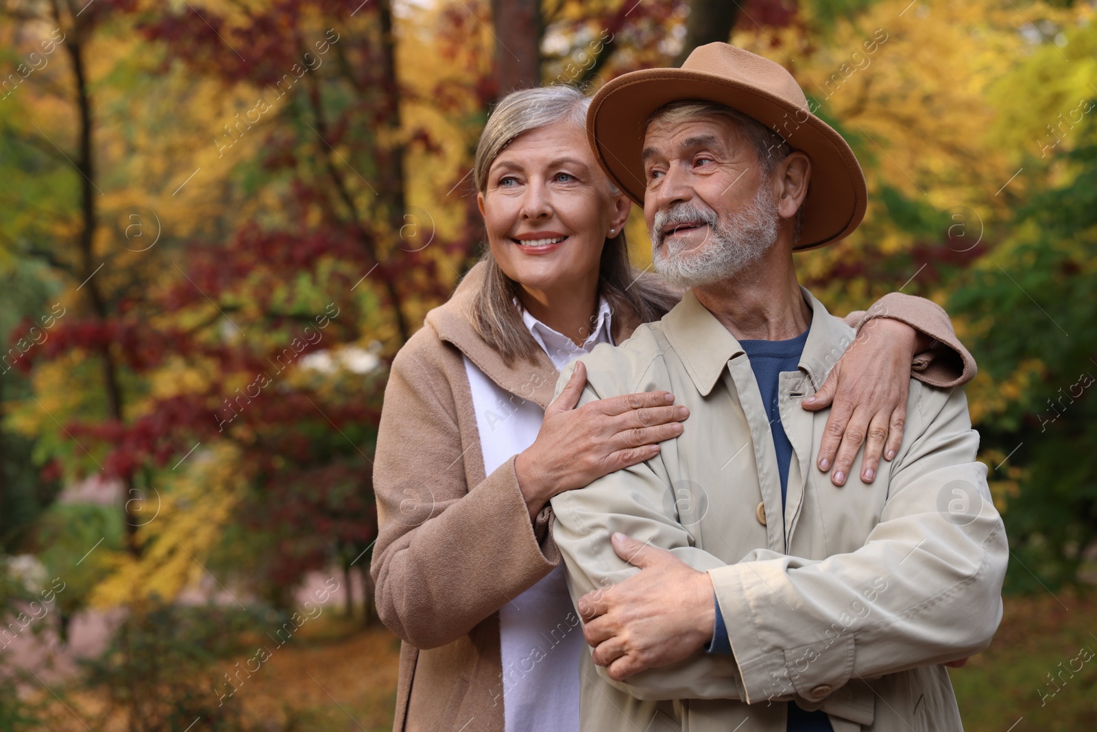 Photo of Portrait of affectionate senior couple in autumn park, space for text