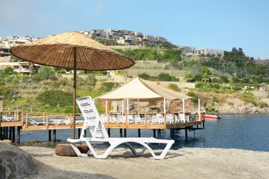 Photo of Lounge chair and beach umbrella on sea shore
