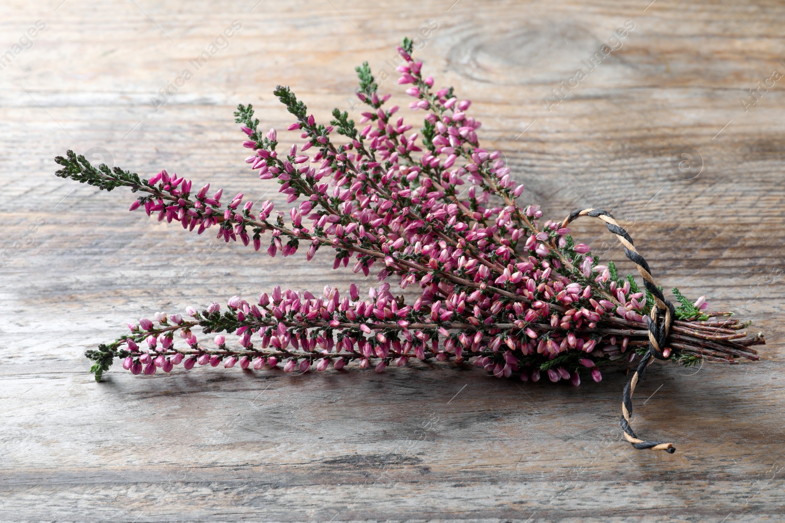 Photo of Bunch of heather branches with beautiful flowers on wooden table