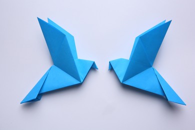 Photo of Beautiful blue origami birds on white background, flat lay.