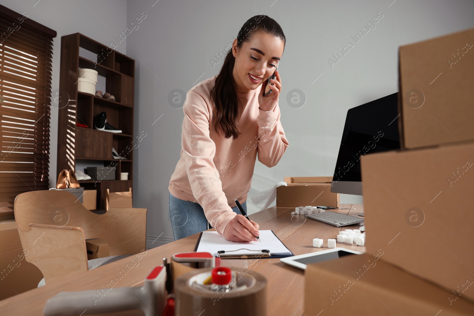 Photo of Seller talking on phone in office. Online store