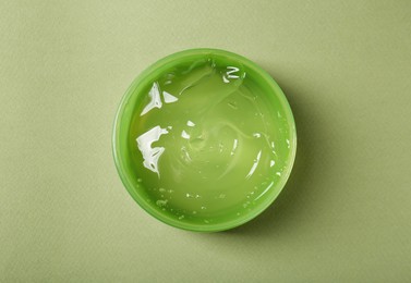 Photo of Aloe gel in jar on olive background, top view