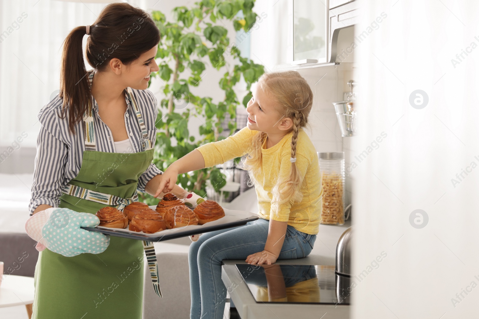 Photo of Daughter and beautiful mother with tray of oven baked buns in kitchen