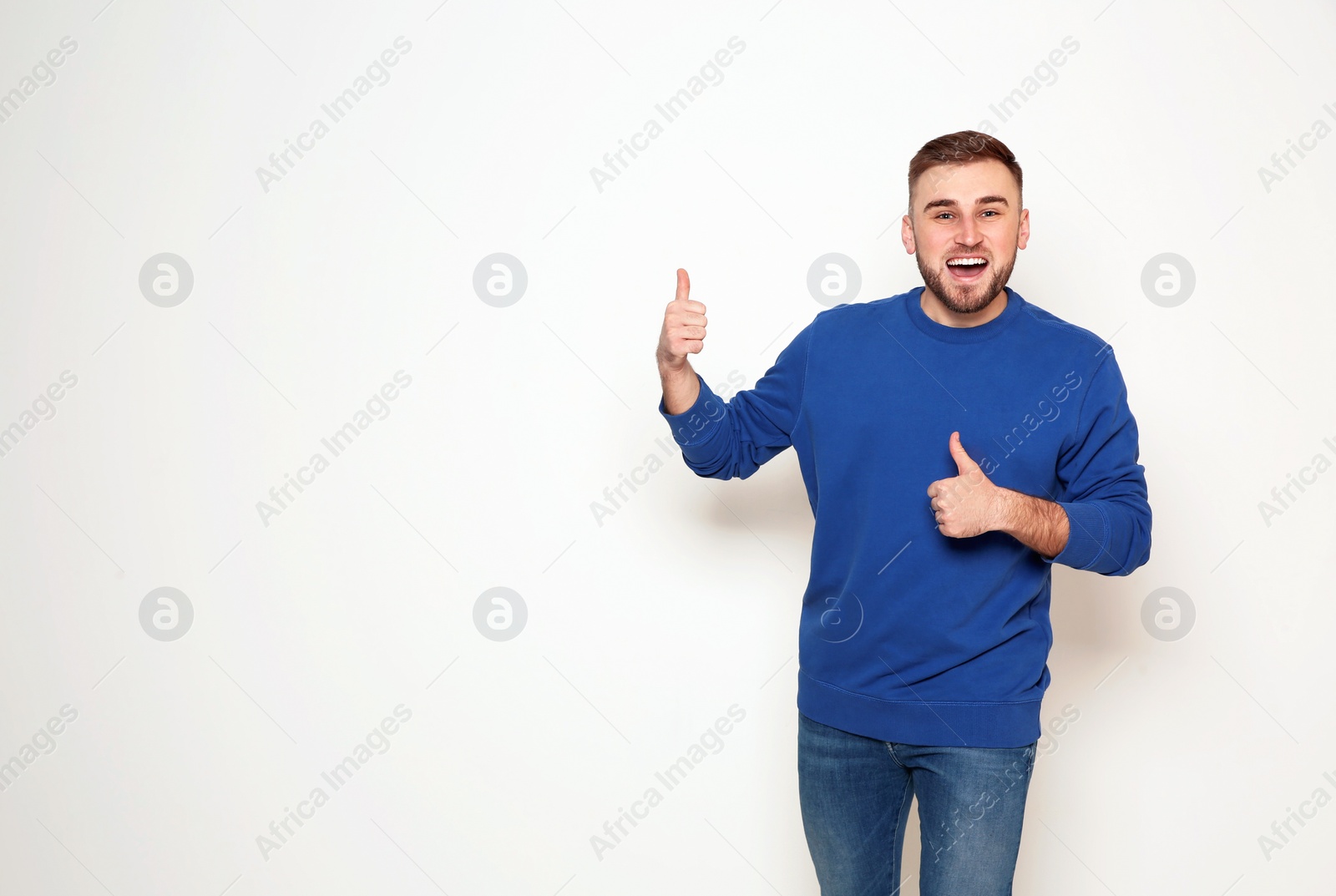 Photo of Portrait of emotional man showing thumbs up gesture on white background