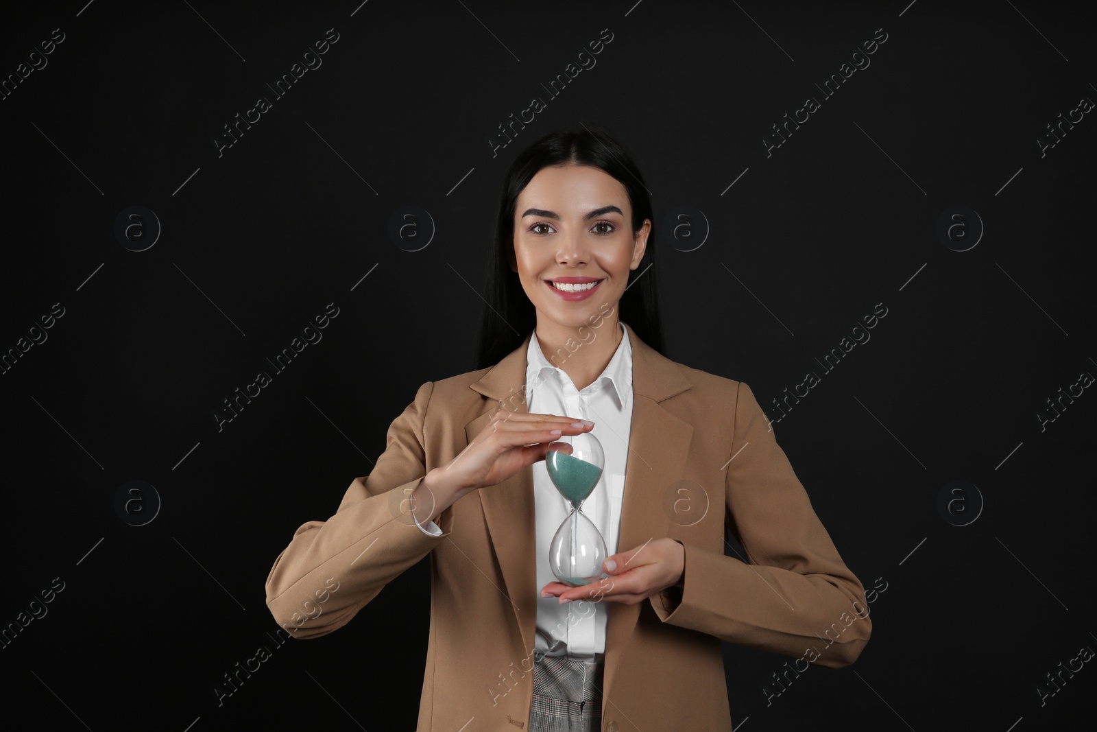 Photo of Businesswoman holding hourglass on black background. Time management