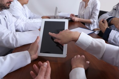 Photo of Team of doctors using tablet during conference indoors, closeup