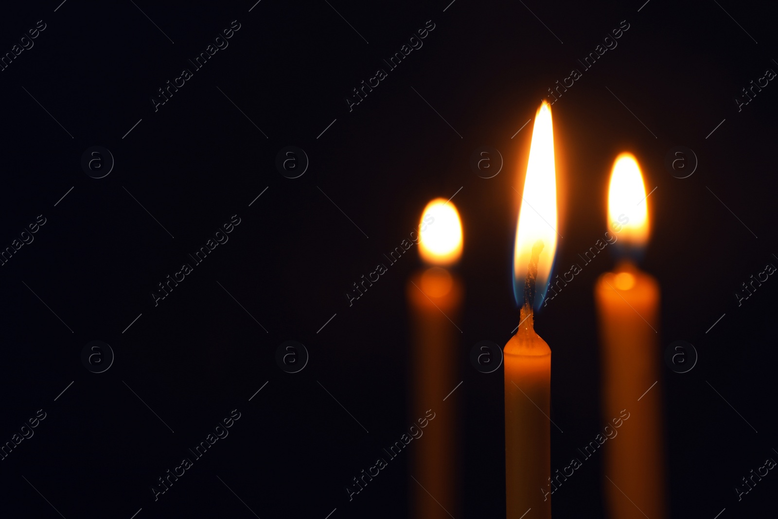 Photo of Burning candles on dark background, space for text. Symbol of sorrow