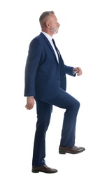 Photo of Businessman imitating stepping up on stairs against white background. Career ladder concept