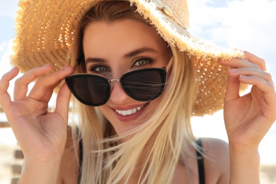 Photo of Beautiful woman wearing sunglasses outdoors on sunny day, closeup