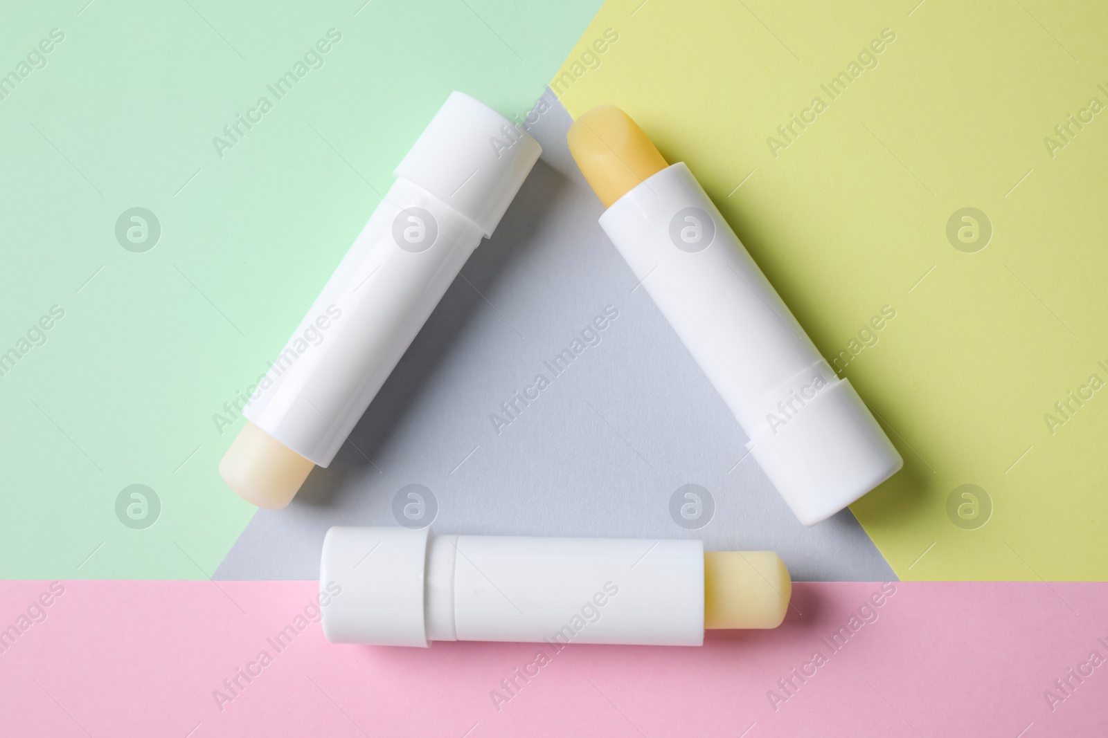 Photo of Hygienic lipsticks on color background, flat lay