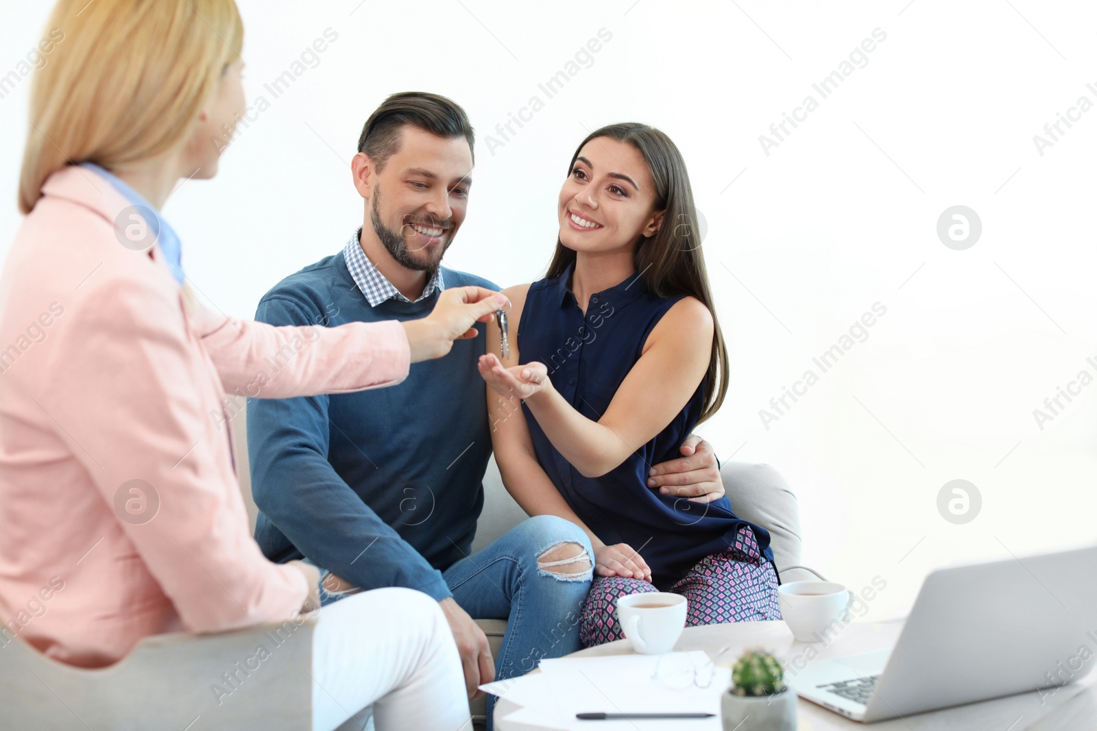 Photo of Female real estate agent giving house key to couple in office