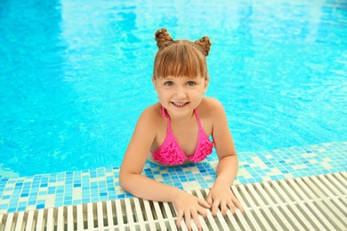 Happy girl resting in blue swimming pool