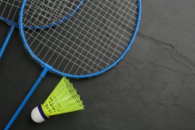 Photo of Rackets and shuttlecock on black background, flat lay with space for text. Badminton equipment