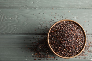 Bowl with black quinoa and space for text on wooden background, top view