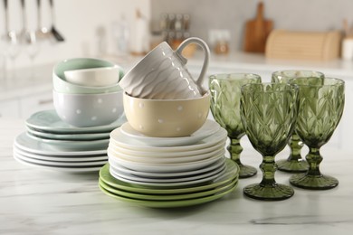 Many different clean dishware, glasses and cup on white marble table indoors