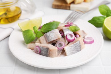 Photo of Plate with tasty marinated fish, onion and basil on light tiled table, closeup