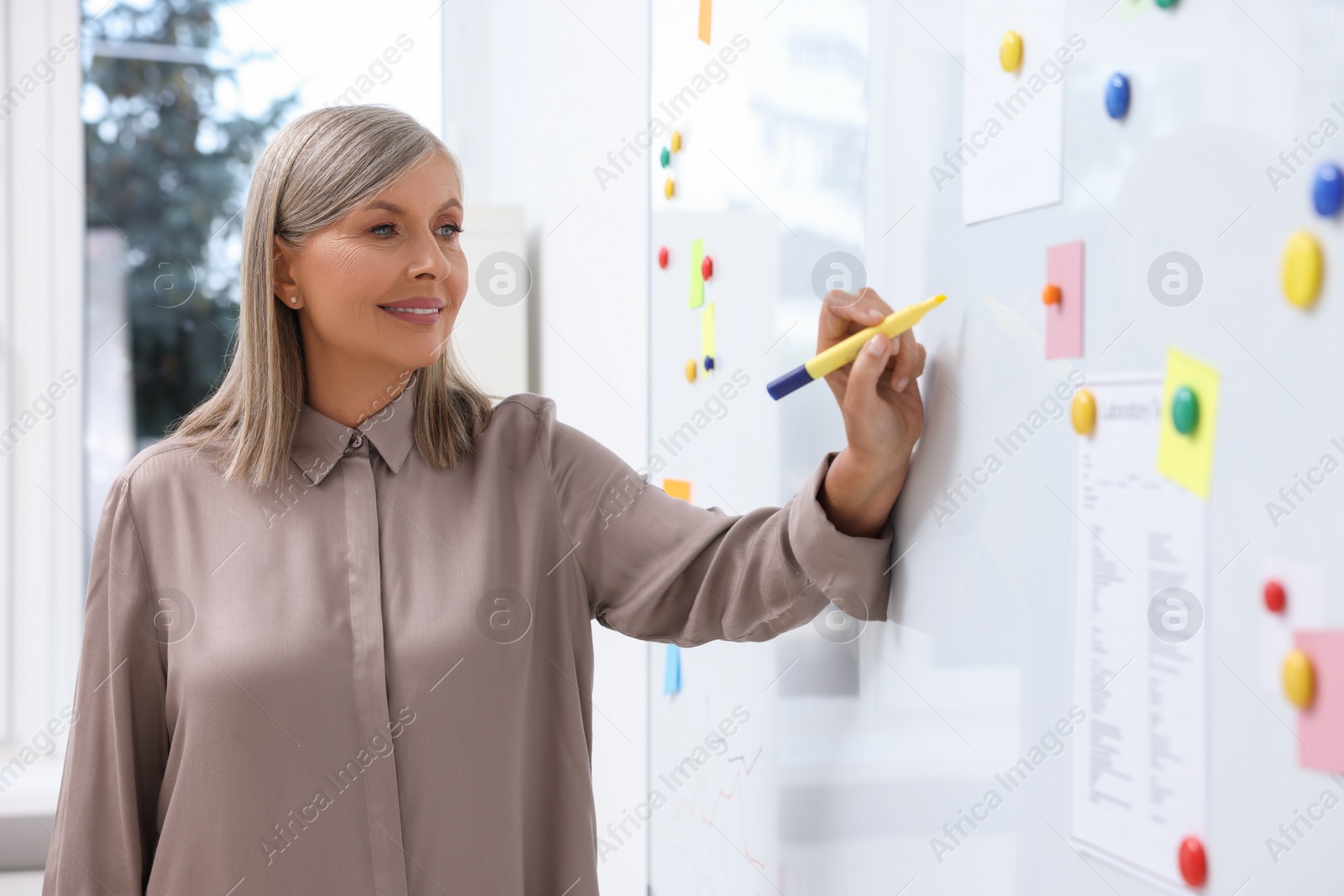 Photo of Professor explaining something with marker at whiteboard in classroom