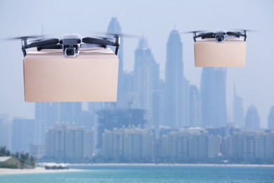Image of Modern drones with carton boxes flying above sea on sunny day. Delivery service 