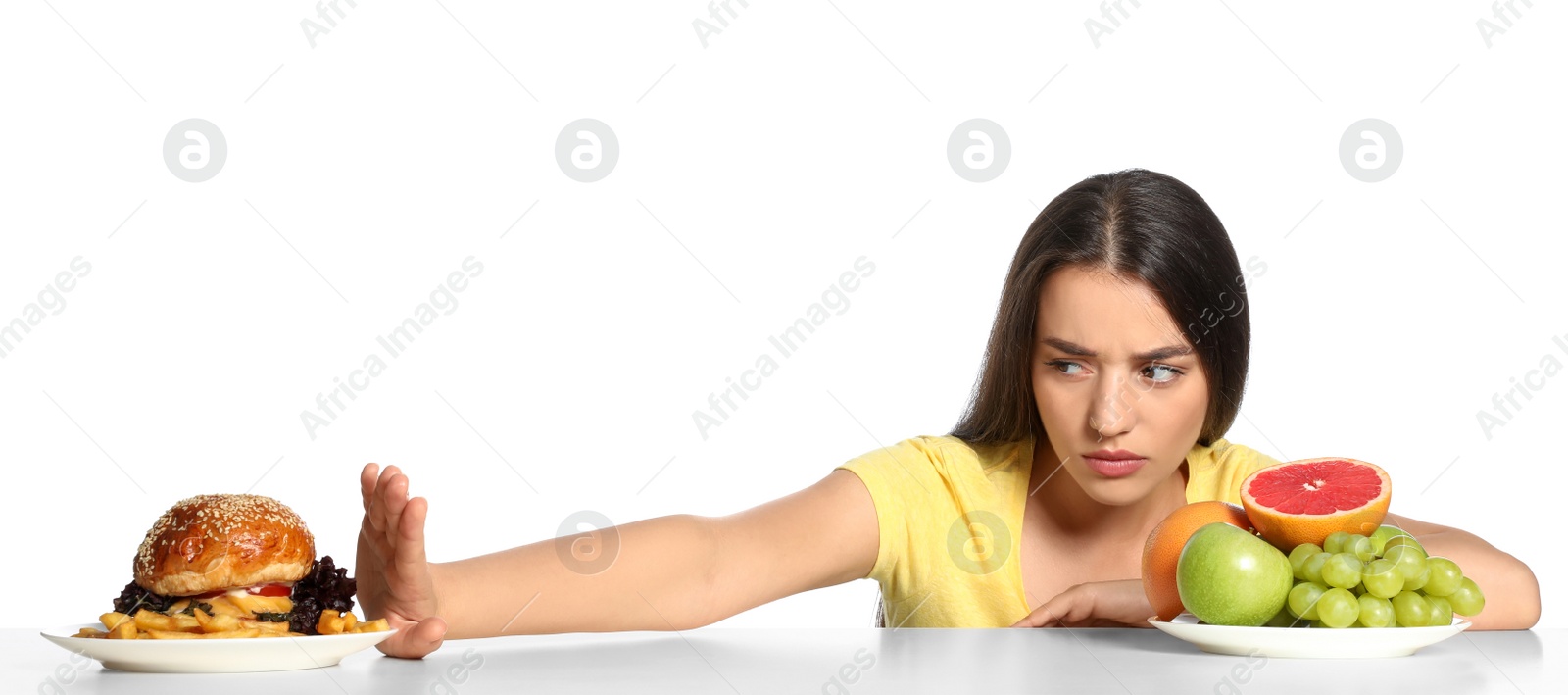 Photo of Woman choosing between fruits and burger with French fries on white background