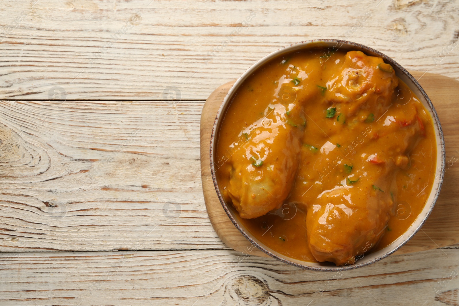 Photo of Tasty chicken curry on wooden table, top view. Space for text