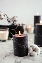Photo of Burning candles and cotton flower with fairy lights on marble table, space for text