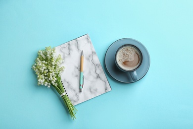 Flat lay composition with notebook, lily of the valley bouquet and coffee on color background