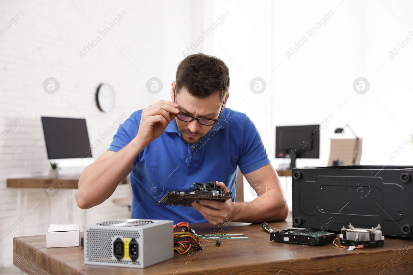 Photo of Male technician repairing computer at table indoors