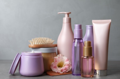Photo of Different hair products, flower and brush on grey table