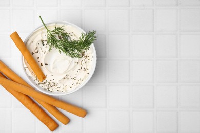 Photo of Delicious cream cheese with grissini sticks and dill on white tiled table, flat lay. Space for text