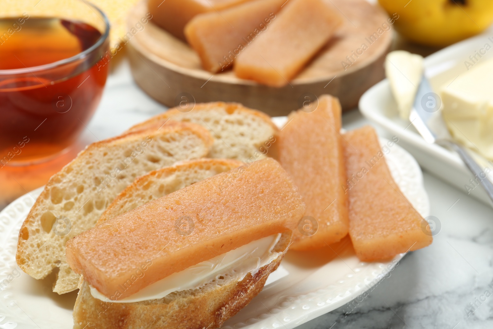 Photo of Delicious quince paste and bread on white marble table, closeup