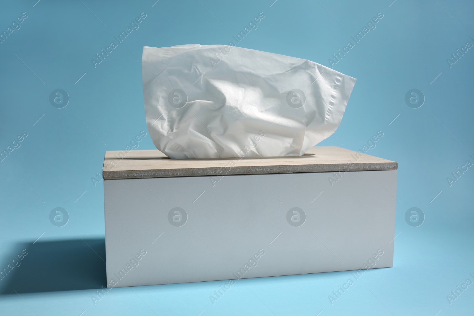 Photo of Holder with paper tissues on light blue background