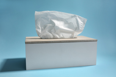 Photo of Holder with paper tissues on light blue background