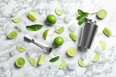 Flat lay composition with lime, mint and shaker on marble background. Refreshing beverage ingredients