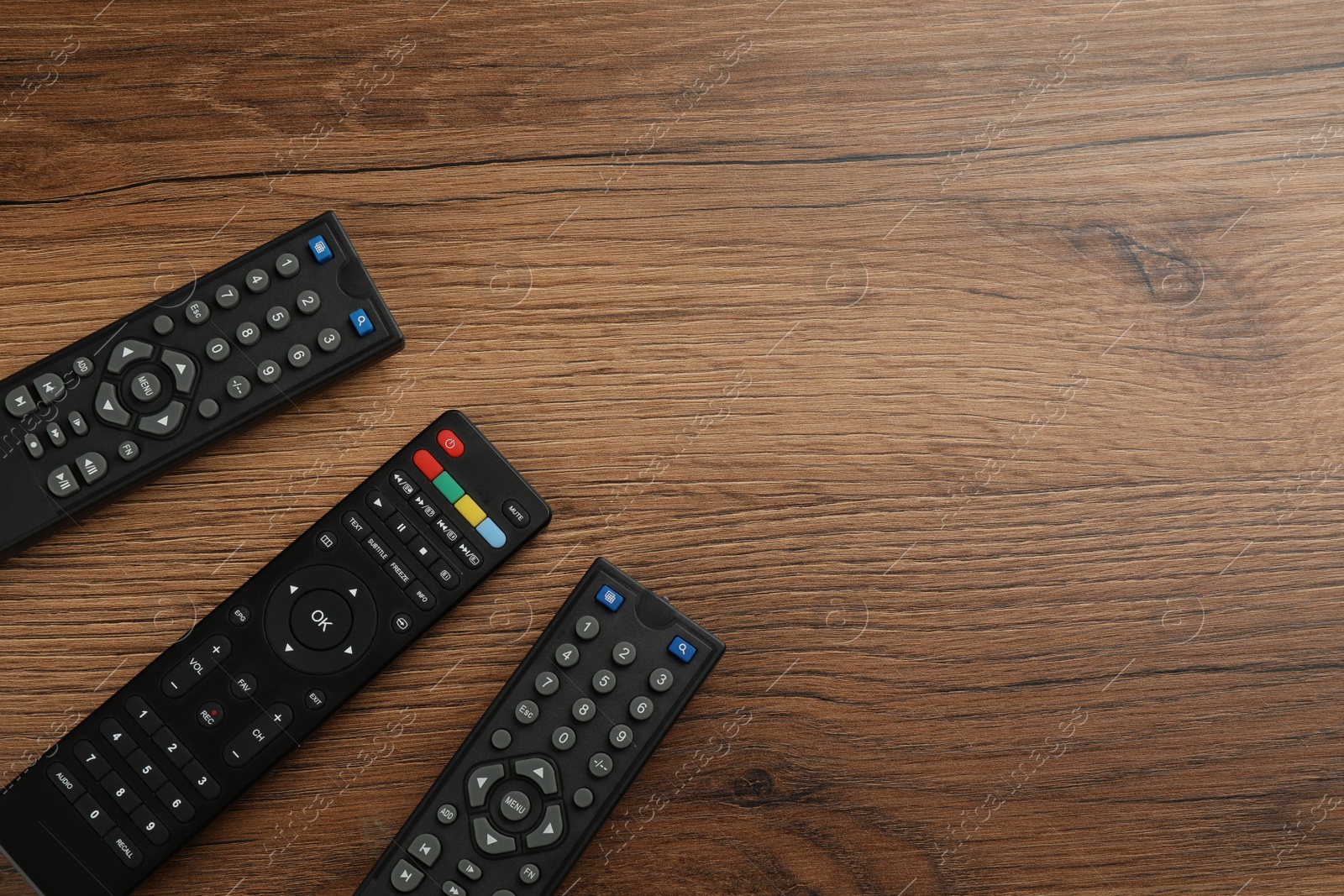 Photo of Modern tv remote controls on wooden table, flat lay. Space for text