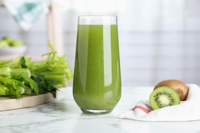 Glass with fresh celery juice on white marble table, closeup