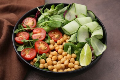 Tasty salad with chickpeas, cherry tomatoes and cucumbers on grey textured table, closeup