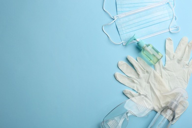 Flat lay composition with medical gloves, masks and hand sanitizers on light blue background. Space for text