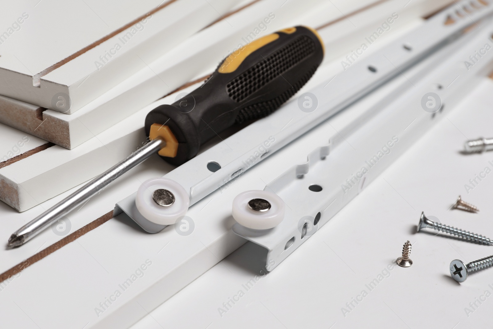 Photo of Furniture assembly parts, screwdriver and different metal fasteners