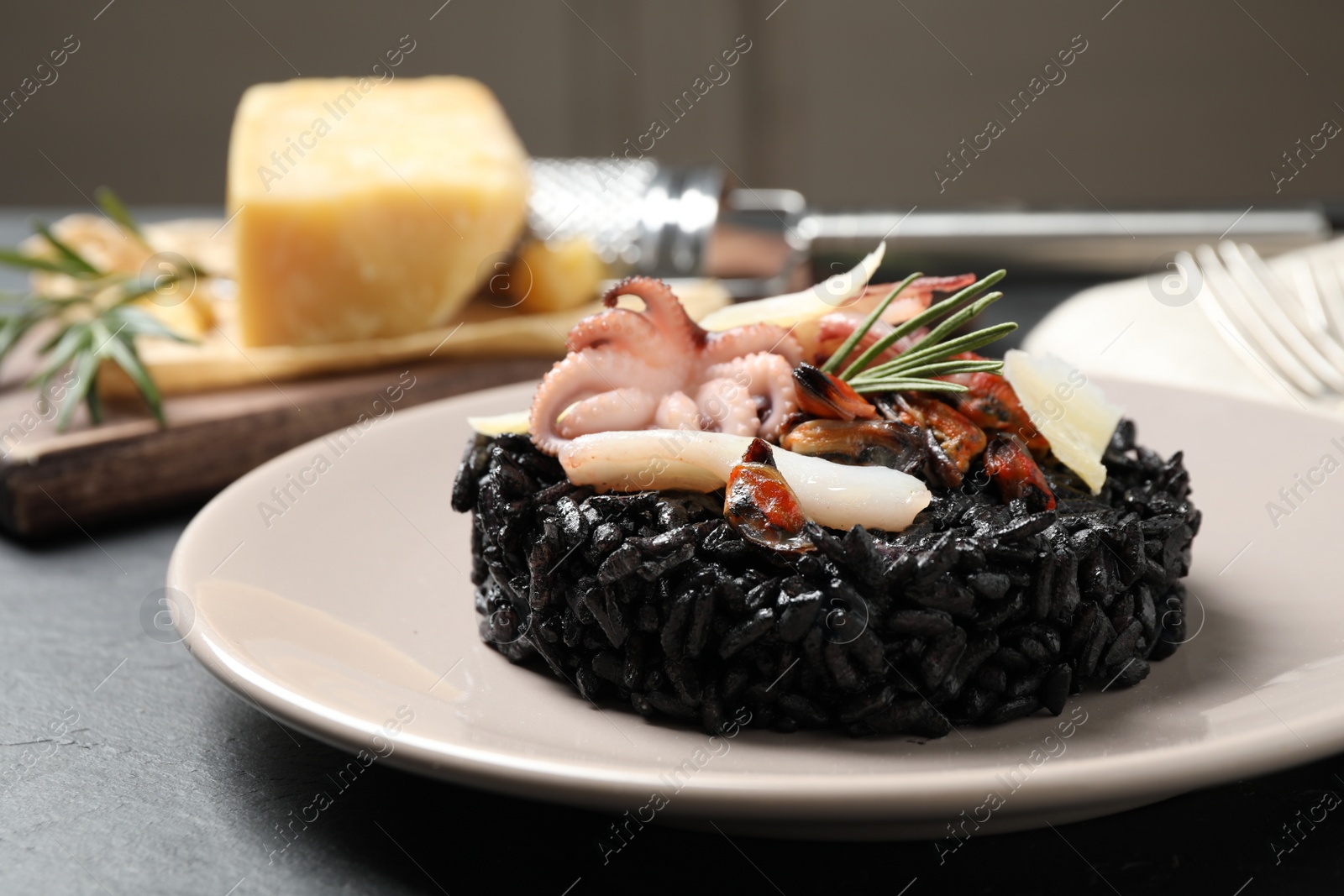 Photo of Delicious black risotto with seafood on grey table