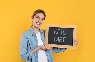 Woman holding blackboard with phrase Keto Diet on yellow background