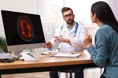 Photo of Neurologist showing brain scan to young woman in clinic