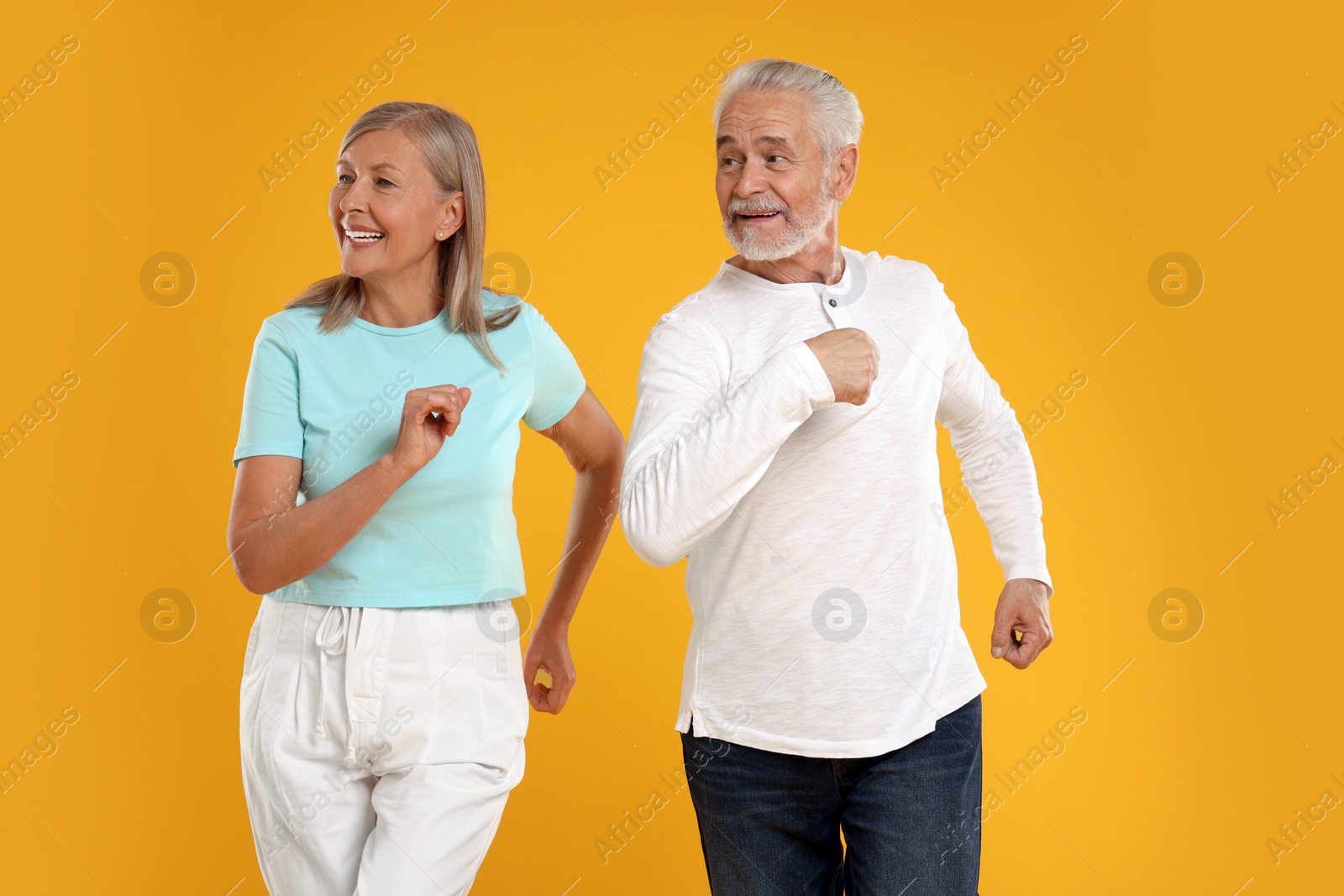 Photo of Senior couple dancing together on orange background