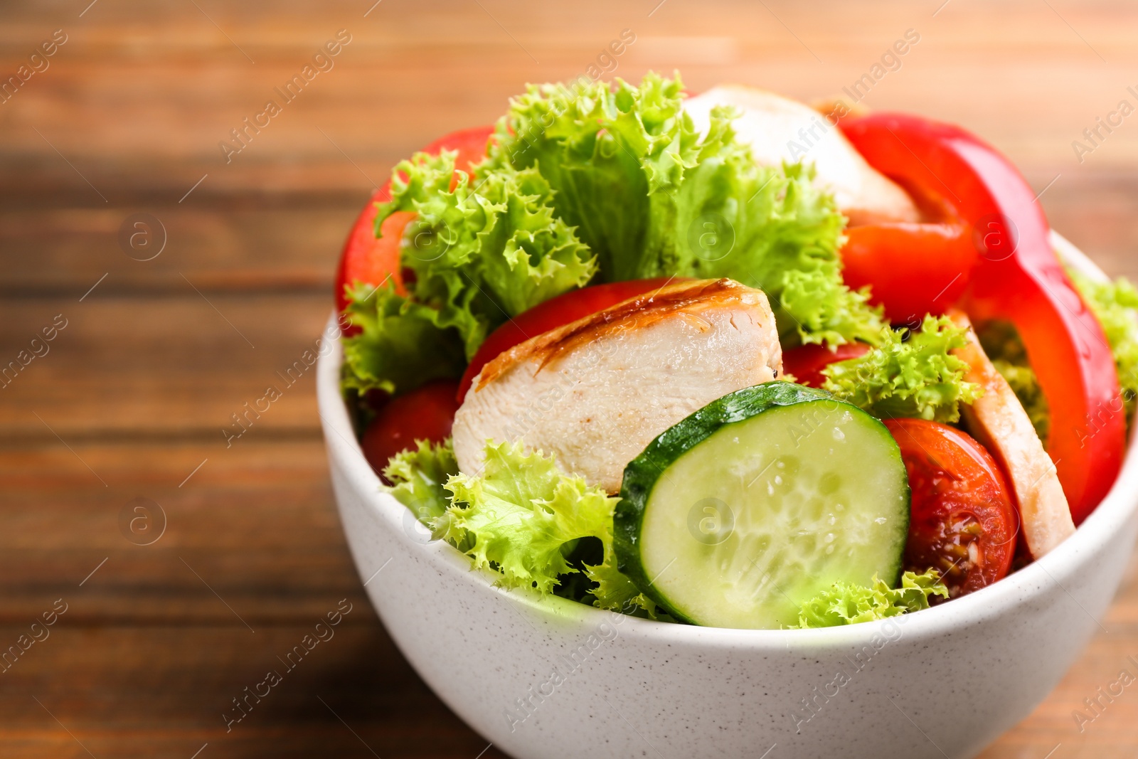 Photo of Delicious salad with chicken and vegetables on table, closeup