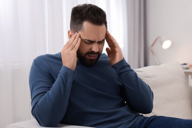 Man suffering from headache on sofa at home