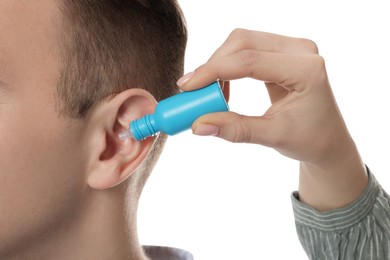 Woman dripping medication into man's ear on white background, closeup