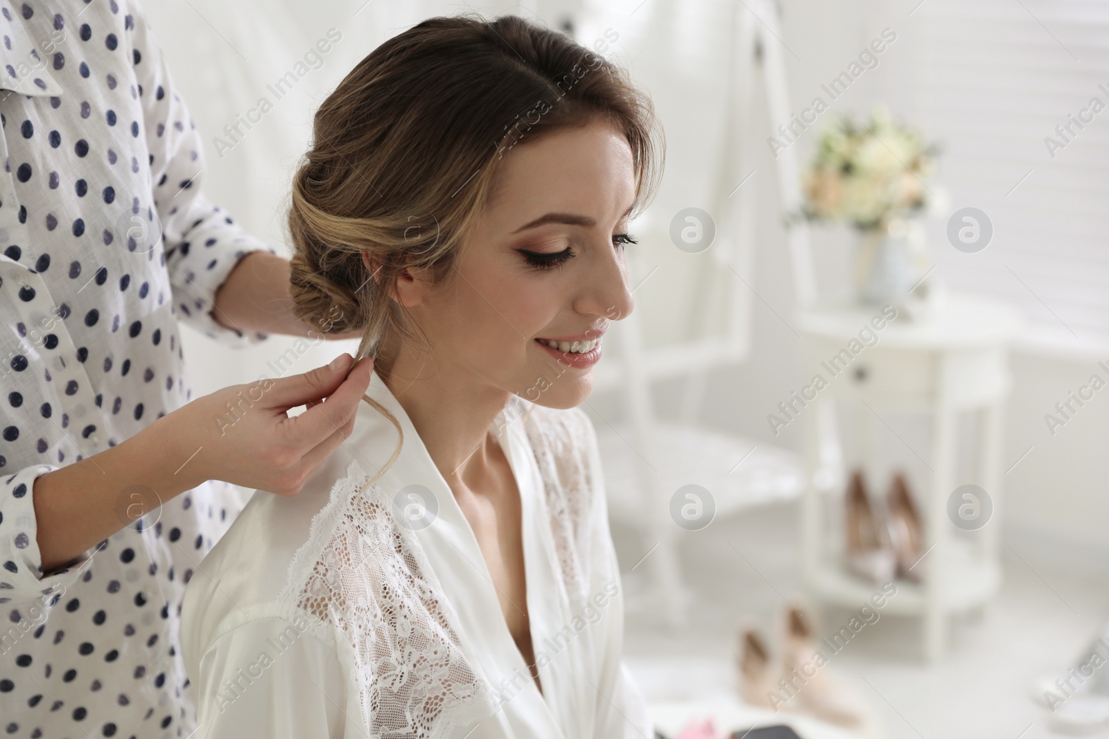 Photo of Professional stylist making wedding hairstyle for bride in salon