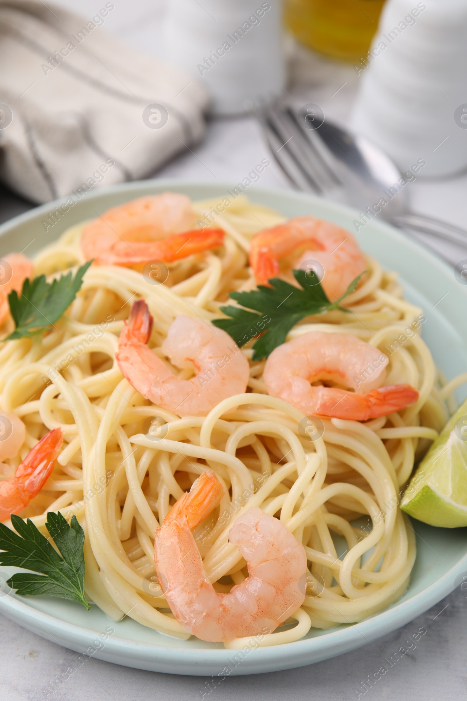 Photo of Tasty spaghetti with shrimps, lime and parsley on table, closeup