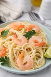 Photo of Tasty spaghetti with shrimps, lime and parsley on table, closeup