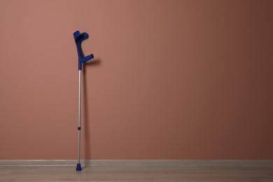 Photo of Elbow crutch near pale pink wall. Space for text