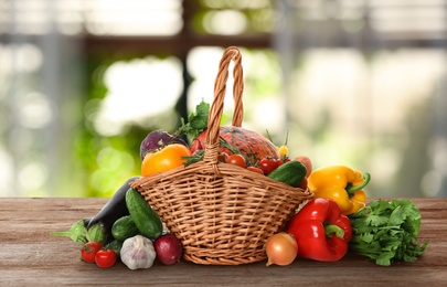 Wicker basket with fresh vegetables on wooden table in kitchen